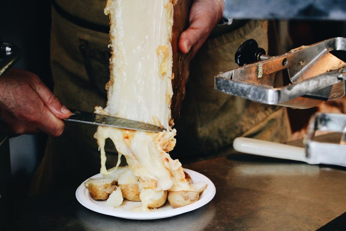 Melted cheese being scraped onto a plate