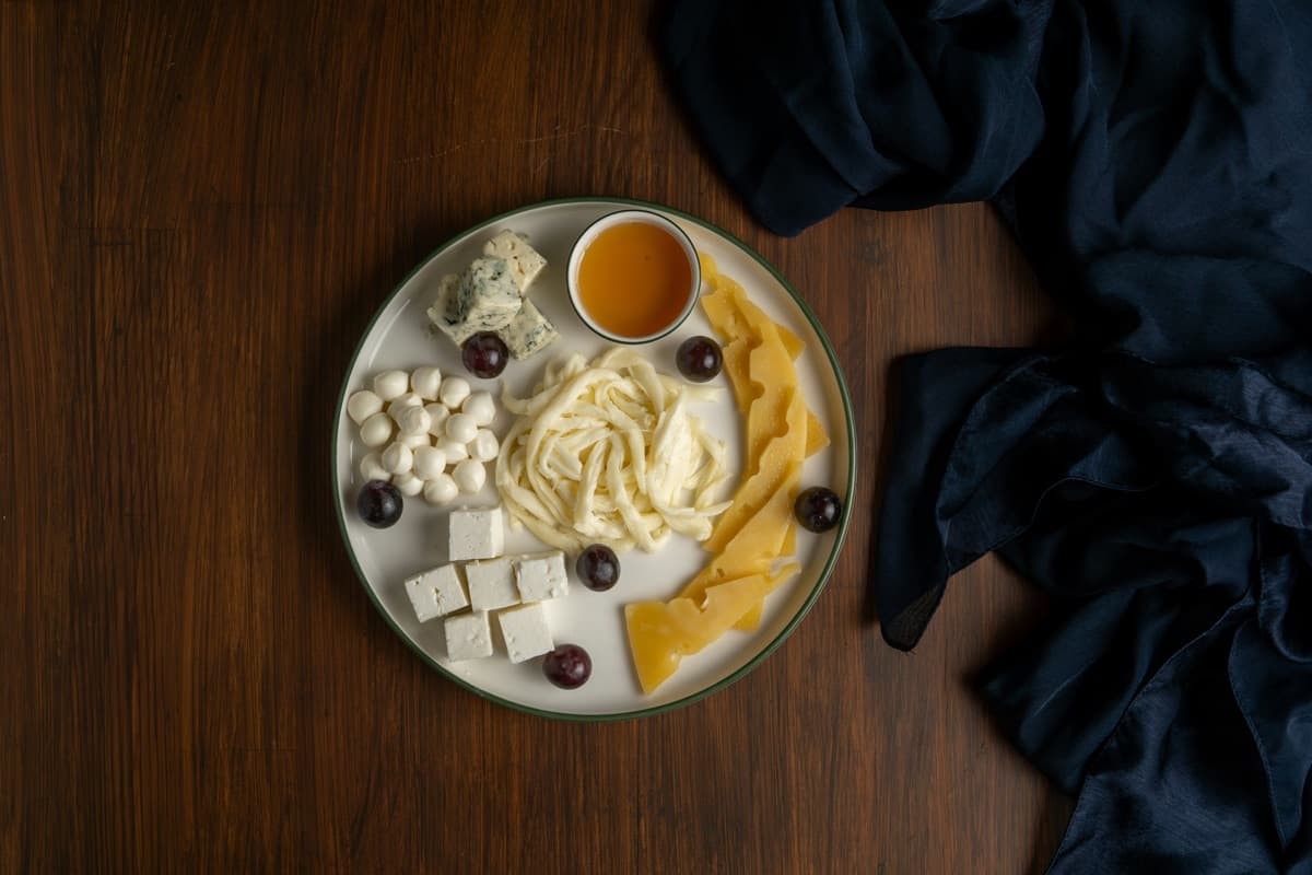A cheese plate from above, with grapes and honey
