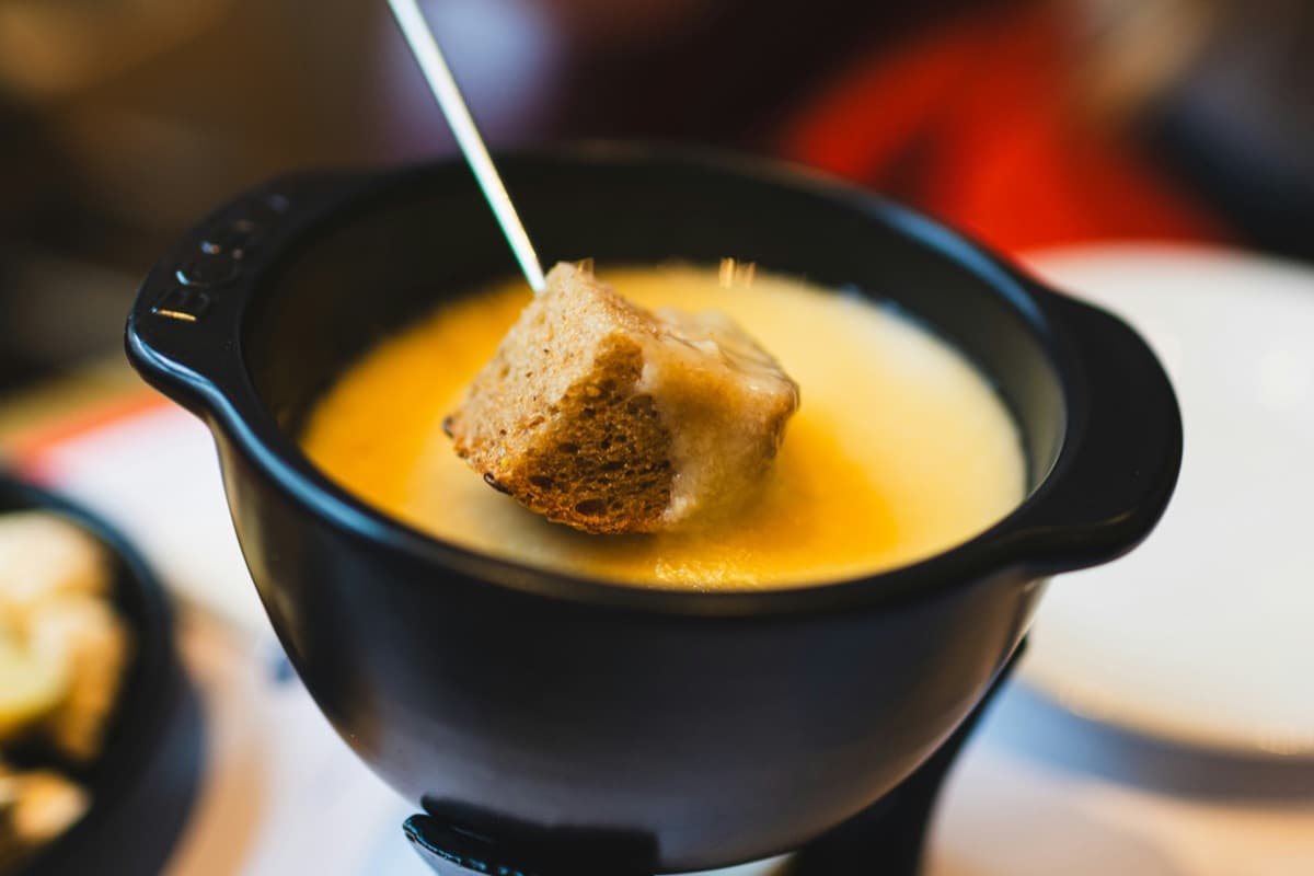 A cube of bread being dipped into a fondue pot